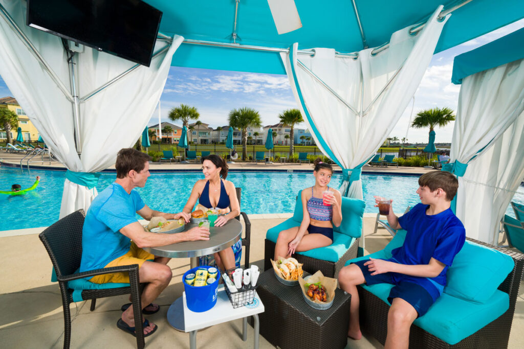 Family of a mom, dad, and two children sharing snacks and drinks under a private cabana at Margaritaville Resort Orlando