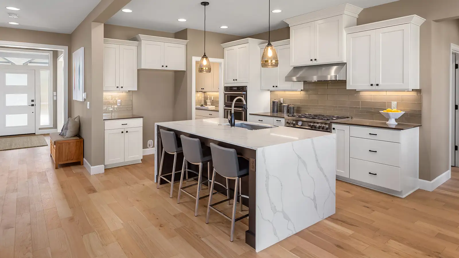 Beautiful kitchen in new luxury home with waterfall island, quartz counter tops, farmhouse sink, and hardwood floors